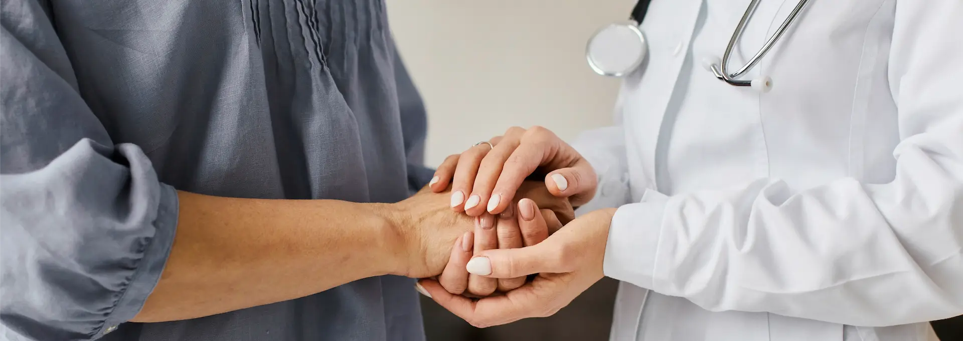 Profesional de la salud sosteniendo las manos de un paciente.
