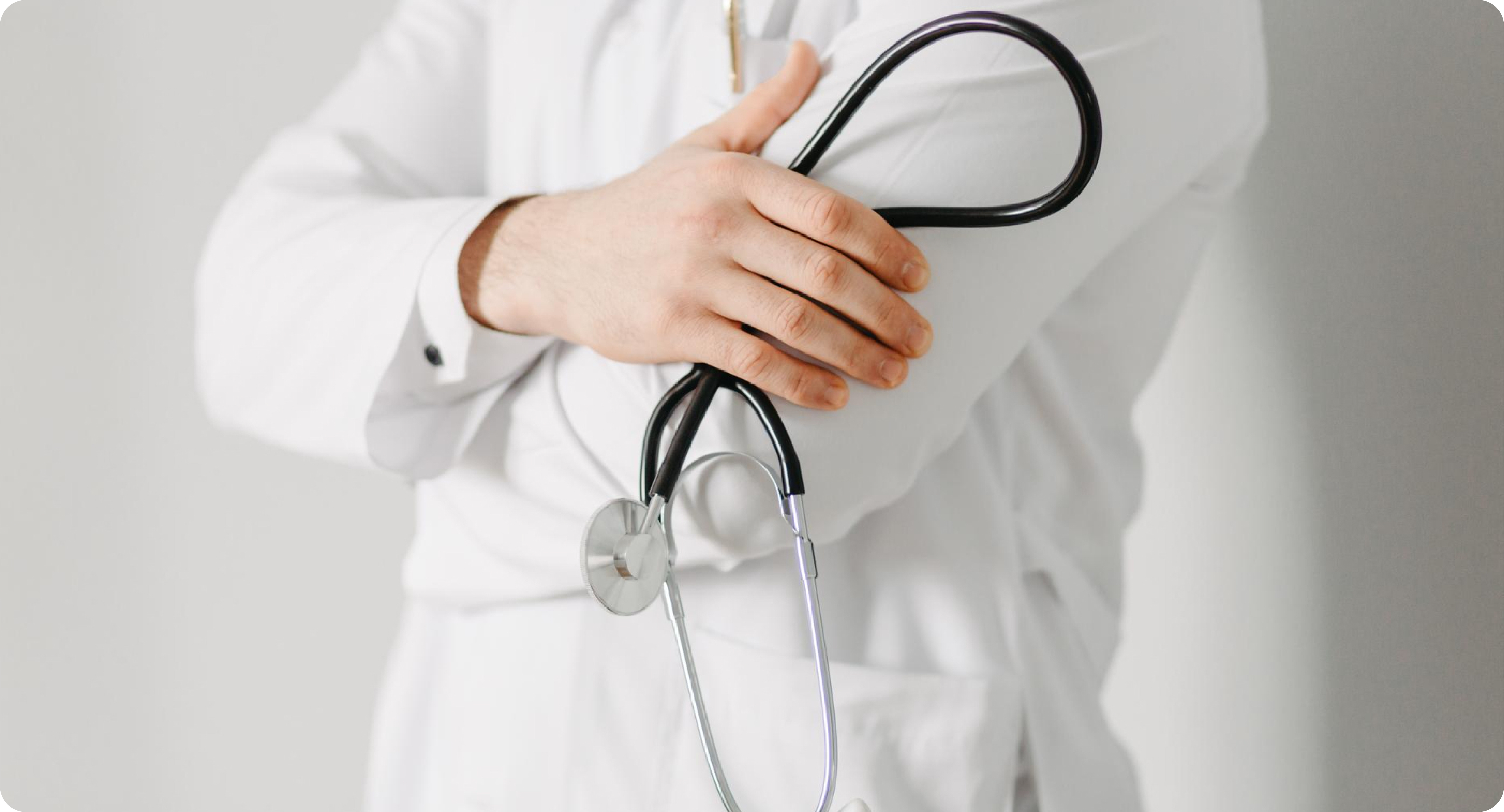 Médico sostiene un fonendoscopio sobre el pecho, listo para una consulta.